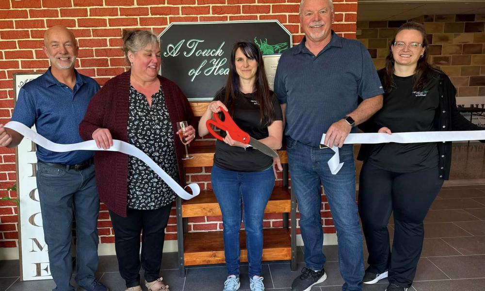 A group of people cut a ribbon for the grand re-opening of A Touch of Health